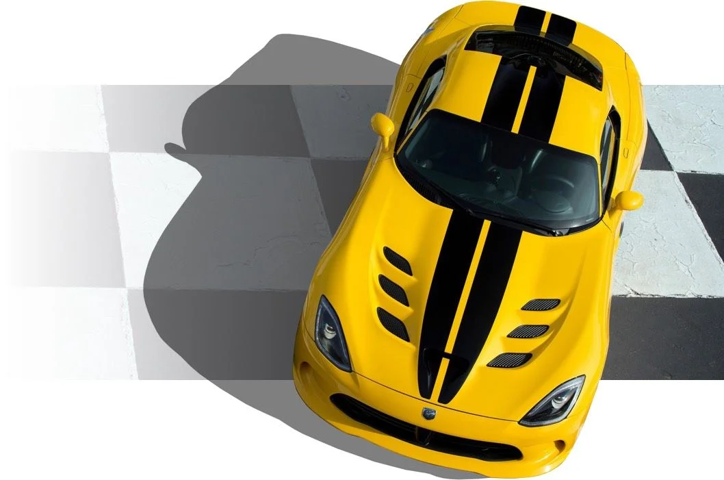 Yellow Dodge Viper with black racing stripes parked on a checkered surface